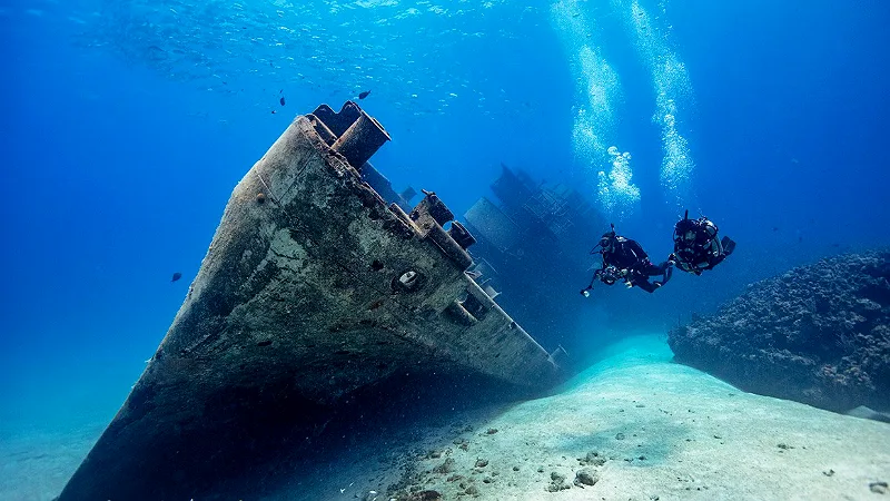 Buzos exploran un barco hundido en aguas azules